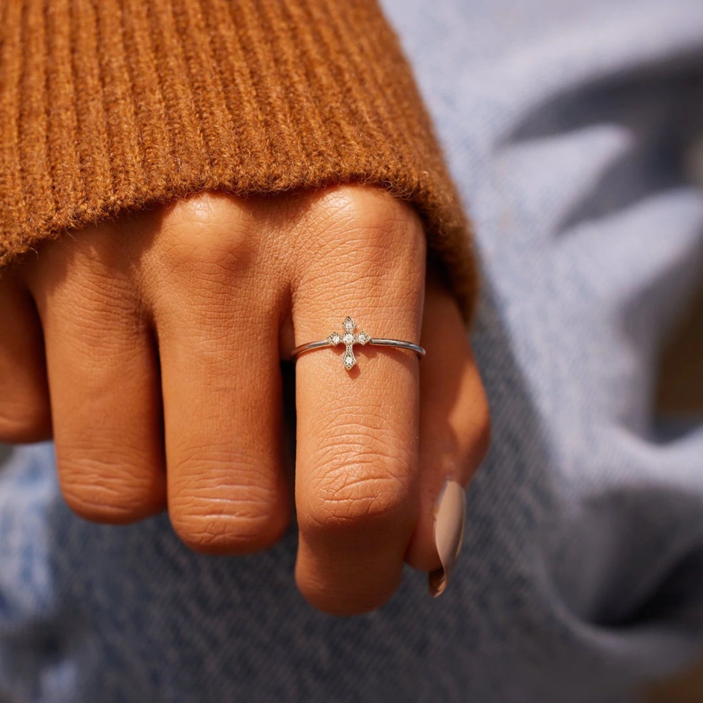 A person's hand wearing a 925 sterling silver ring with a cross design on the finger.